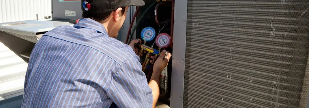 HVAC technician servicing a condenser unit in Kokomo